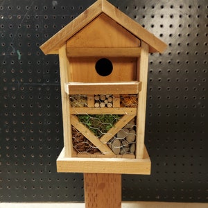 May include: A wooden birdhouse with a nesting box on top and a variety of compartments below for insects. The compartments are filled with natural materials like twigs, pine cones, and moss.