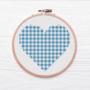 May include: A blue and white gingham heart pattern cross-stitched on white fabric in a wooden embroidery hoop.
