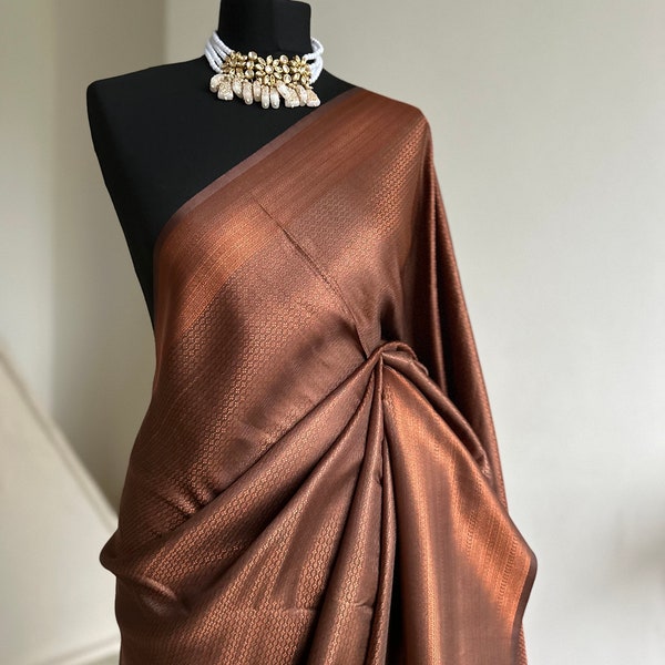 Sari en soie douce brun chocolat et cuivre avec une bordure subtile et un éclat intégral. Le sari parfait pour les fêtes et tous les événements traditionnels.