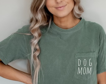May include: A green t-shirt with a pocket that says "DOG MOM" in white text.