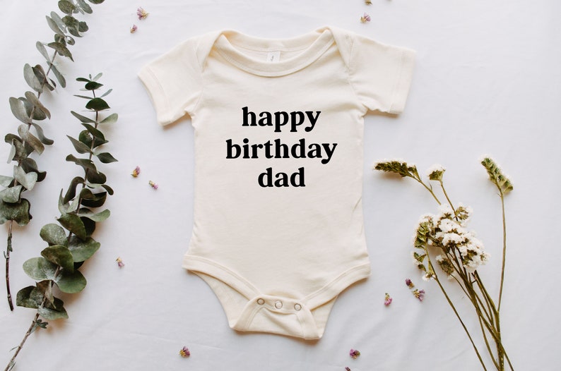 May include: A white baby onesie with black text that reads "happy birthday dad".