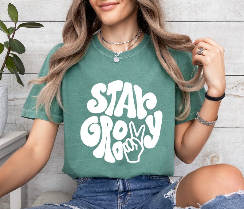 May include: A green t-shirt with a white graphic that says "Stay Groovy" with a peace sign.