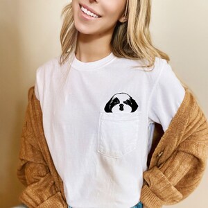 May include: White t-shirt with a black and white dog illustration in the pocket.