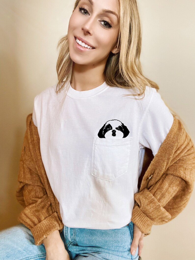 May include: White t-shirt with a black and white dog illustration in the pocket.