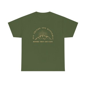 May include: Green t-shirt with a mountain range graphic and the text "All things are difficult before they are easy."