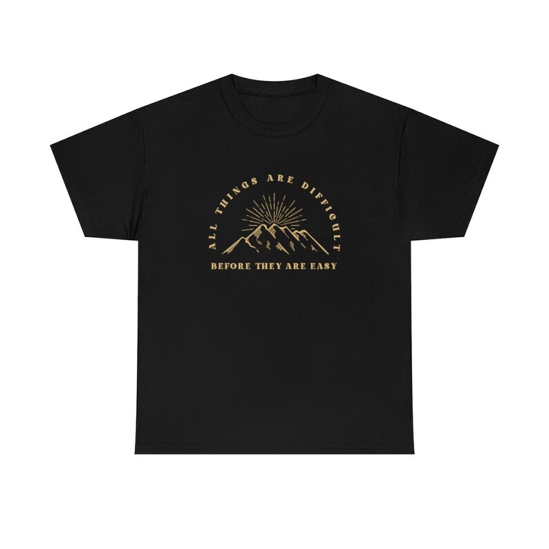 May include: Black t-shirt with a gold graphic of mountains and a sun with the text "All things are difficult before they are easy."