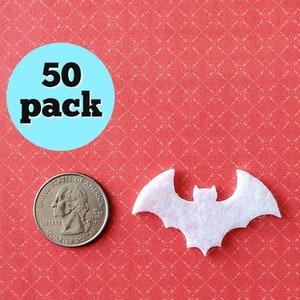 May include: A pack of 50 white felt bat cutouts. The bats are about the size of a US quarter. The bats are on a red background with a white pattern.