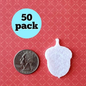 May include: A pack of 50 white felt acorn shapes. The acorns are about the size of a US quarter.