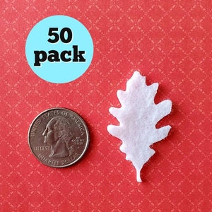May include: A pack of 50 white felt oak leaves. The leaves are about the size of a US quarter.