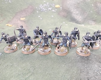 May include: A group of ten miniature figures, painted in black and grey, holding swords and shields. The figures are standing on round bases.