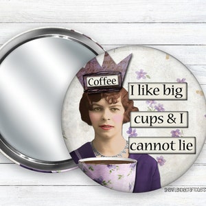 May include: A round compact mirror with a white background and a vintage-style illustration of a woman wearing a crown that says "Coffee". The woman is holding a large coffee cup and the text "I like big cups & I cannot lie" is printed below her.