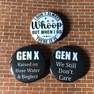 May include: Three round black and white buttons with text. The top button is white with black text that reads "I don't always whoop but when I do there it is". The two bottom buttons are black with white text. The left button reads "Gen X Raised on Hose Water & Neglect". The right button reads "Gen X We Still Don't Care".