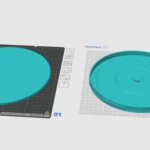 Puede incluir: Se muestran dos objetos circulares de color turquesa. Uno es un disco plano y el otro es una tapa con un borde elevado y un agujero central. Ambos están sobre una superficie gris claro con un patrón de cuadrícula, lo que sugiere un contexto de modelado o impresión 3D.