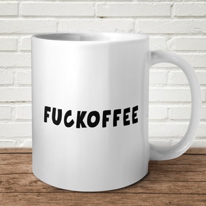 May include: White ceramic coffee mug with black text that reads "FUCKOFFEE".