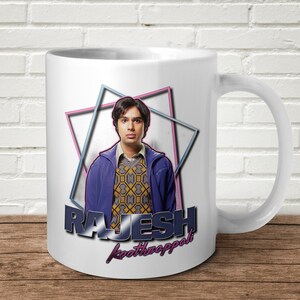 Puede incluir: Taza de cerámica blanca con un gráfico colorido de un hombre con el texto "RAJESH Koothrappali" en un estilo retro de los años 80.
