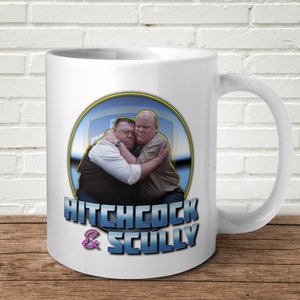May include: White ceramic mug with a blue and yellow circle graphic featuring two men hugging. The text "HITCHCOCK & SCULLY" is printed below the circle.