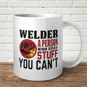 May include: White ceramic mug with a black and red design. The mug features a welder with a welding torch and the text "Welder A Person Who Fixes Stuff You Can't".