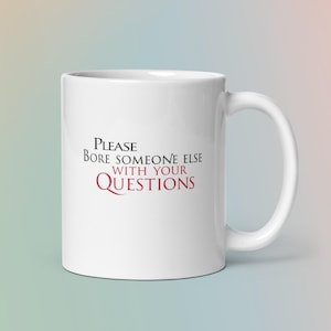 Puede incluir: Taza de cerámica blanca con asa curvada. La taza presenta el texto "Please Bore Someone Else With Your Questions" en letras negras y burdeos. La taza está diseñada para bebidas.