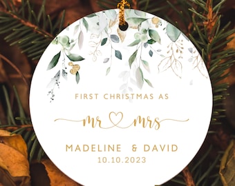 May include: White round Christmas ornament with a gold floral design and the text "First Christmas as Mr & Mrs Madeline & David 10.10.2023".