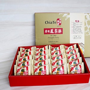 May include: A red box filled with individually wrapped pineapple pastries. The box has a gold lid with the text "ChiaTe" and "鳳梨酥" in Chinese characters. The lid also has the text "Pineapple Pastry" in English.