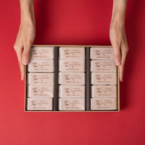 May include: A box of 18 individually wrapped pineapple cakes. The cakes are packaged in brown boxes with a cartoon of a person riding a bicycle and the text "Sunny Hills Pineapple Cake".