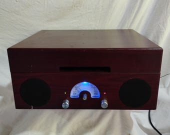 以下が含まれることがあります： ダークレッド仕上げの木製レコードプレーヤー。黒いスピーカー2つ、青く光るダイヤル、シルバーのノブが特徴です。クラシックな美学を呼び起こし、レコード愛好家に最適です。