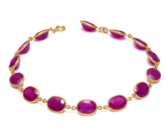 May include: A gold chain bracelet with oval-shaped pink gemstones.