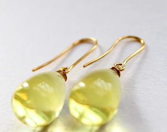 May include: A pair of gold earrings with teardrop-shaped yellow gemstones.