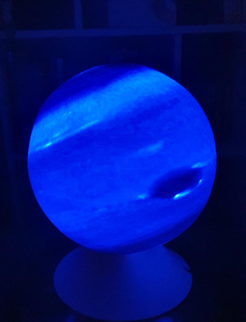 May include: A blue and white globe-shaped night light with a white base. The globe is lit from within, creating a blue glow.