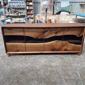 May include: A dark brown wooden cabinet with four drawers and a unique epoxy resin inlay. The cabinet has a modern design and is perfect for a living room or dining room.