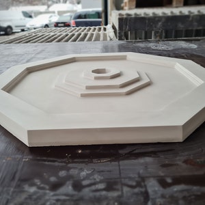 K&ouml;nnte beinhalten: Ein wei&szlig;es achteckiges Dekorationsst&uuml;ck mit konzentrischem Kreisdesign. Das St&uuml;ck hat eine glatte, matte Oberfl&auml;che und ist aus einem strapazierf&auml;higen Material gefertigt.