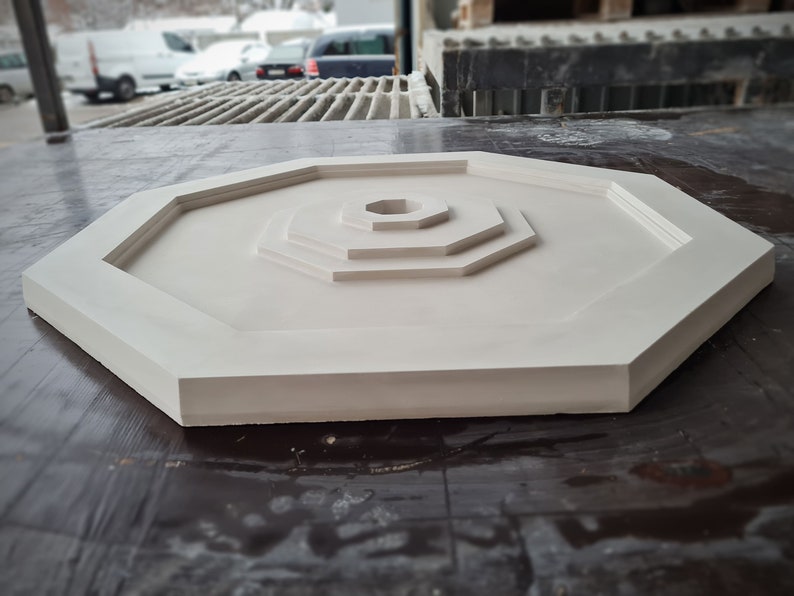 K&ouml;nnte beinhalten: Ein wei&szlig;es achteckiges Dekorationsst&uuml;ck mit konzentrischem Kreisdesign. Das St&uuml;ck hat eine glatte, matte Oberfl&auml;che und ist aus einem strapazierf&auml;higen Material gefertigt.