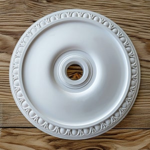 May include: White ceiling medallion with a decorative border and a central hole for a light fitting.