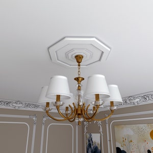 K&ouml;nnte beinhalten: Ein goldener Kronleuchter mit wei&szlig;en Lampenschirmen h&auml;ngt an einer wei&szlig;en Decke mit dekorativen Leisten. Der Kronleuchter hat ein Kristall-Mittelst&uuml;ck und eine Kette.