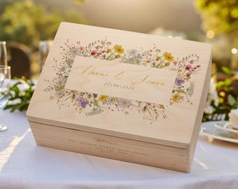 May include: A light-colored wooden box with a floral design and the names "Naomi & Simon" and the date "201042026" printed on the lid. The box is sitting on a white tablecloth.