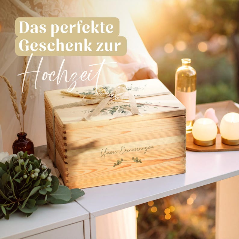 AMARI Erinnerungskiste Hochzeit Pflanzenwelt mit Schleife auf einem Tisch neben Kerzen, dazu der Schriftzug „Das perfekte Geschenk zur Hochzeit“.