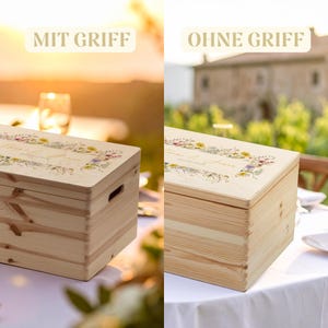 Op de afbeelding: Twee houten kisten, &eacute;&eacute;n met en &eacute;&eacute;n zonder handvat, worden op een tafel getoond. Beide kisten hebben een lichte houten afwerking en bloemmotieven op de deksels. De tekst "MIT GRIFF" en "OHNE GRIFF" staat boven de kisten.