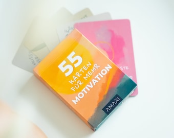 May include: A deck of 55 orange and blue motivational cards with the text "55 Karten für mehr Motivation" and the brand name "AMARI" printed on the front.