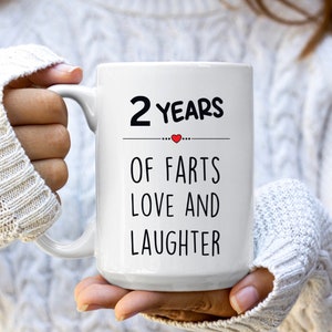 May include: White ceramic coffee mug with black text that reads "2 Years of Farts Love and Laughter" with a small red heart.