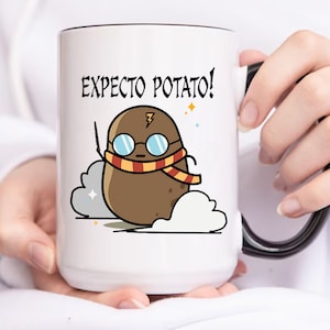 Puede incluir: Taza de cerámica blanca con borde y asa negros. La taza presenta un personaje de dibujos animados de patata con gafas, bufanda y varita, con las palabras "Expecto Potato!" impresas encima. La patata está sobre un fondo de nubes.