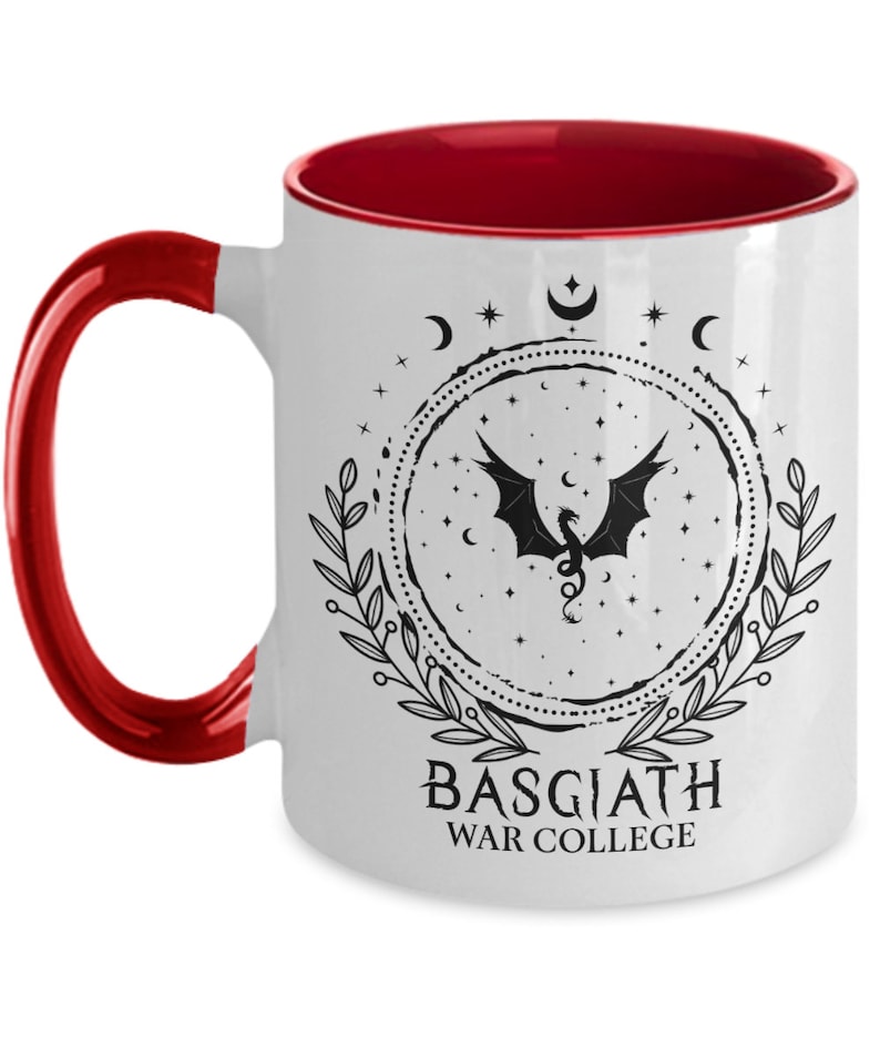 May include: White ceramic mug with a red interior and handle. The mug features a black dragon design within a circular frame, surrounded by stars, moons, and leaves. The text "BASGIATH WAR COLLEGE" is printed below the design.