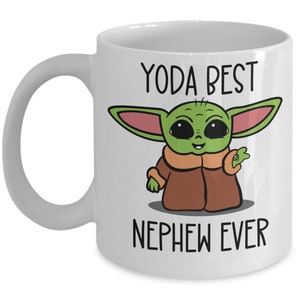 May include: White ceramic mug with a green cartoon character with big eyes and the text "Yoda Best Nephew Ever".