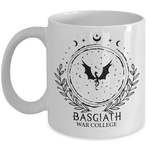 May include: White ceramic mug featuring a black dragon design within a circular frame of stars, moons, and leaves. The text "BASGIATH WAR COLLEGE" is printed below the design. The mug has a curved handle.