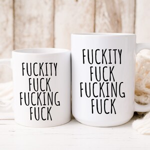 May include: Two white ceramic mugs with black text. The text on both mugs reads "F*ckity F*ck F*cking F*ck".
