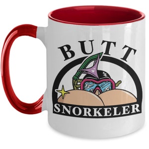 May include: White ceramic mug with a red interior and handle. The mug features the words "BUTT SNORKELER" in black, with a cartoon illustration of a snorkel mask and bikini bottoms.
