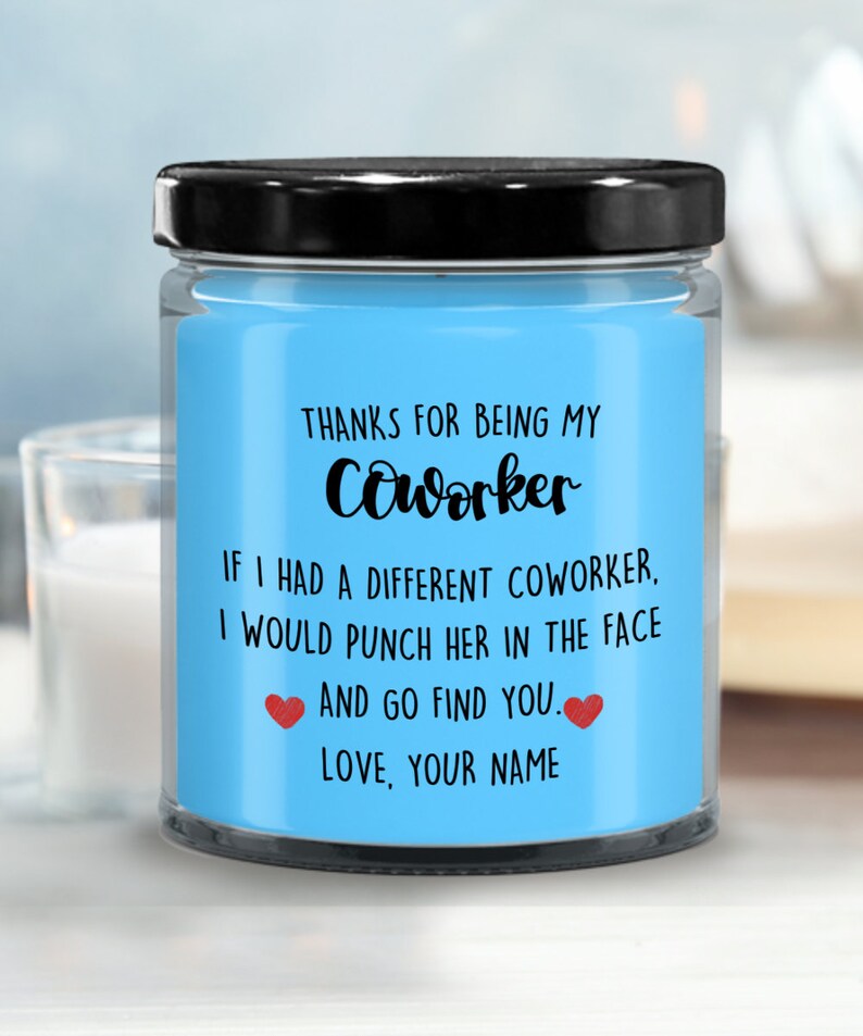 May include: A blue glass candle jar with a black lid. The label reads "Thanks for being my coworker. If I had a different coworker, I would punch her in the face and go find you. Love, your name."