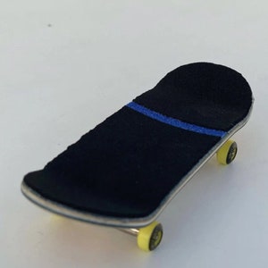 May include: A miniature skateboard with a black grip tape featuring a blue stripe. The deck has a natural wood finish, and the wheels are yellow. This fingerboard is designed for tricks and stunts.