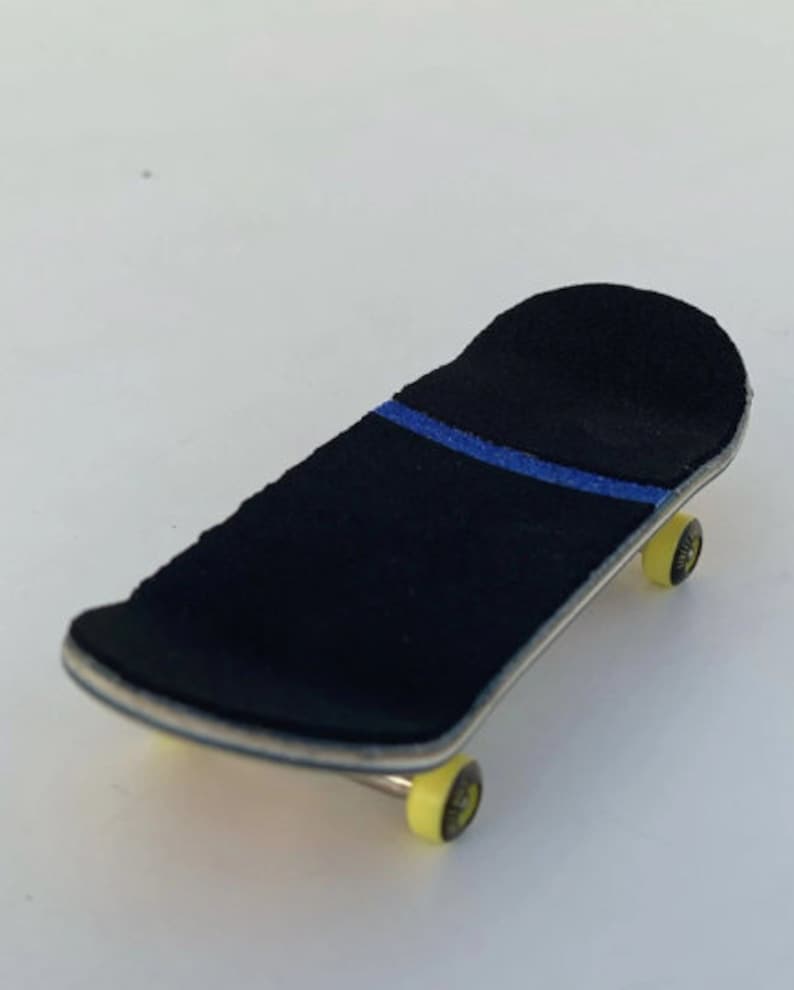 May include: A miniature skateboard with a black grip tape featuring a blue stripe. The deck has a natural wood finish, and the wheels are yellow. This fingerboard is designed for tricks and stunts.