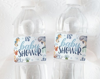 May include: Two clear plastic water bottles with blue and white labels that say "baby shower" with sea creatures and bubbles. The bottles are on a white plate with a white background.