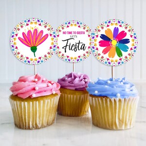 Könnte beinhalten: Drei Cupcake-Topper mit bunten Blumenmustern und dem Text "Keine Zeit für Siesta, lasst uns feiern!"